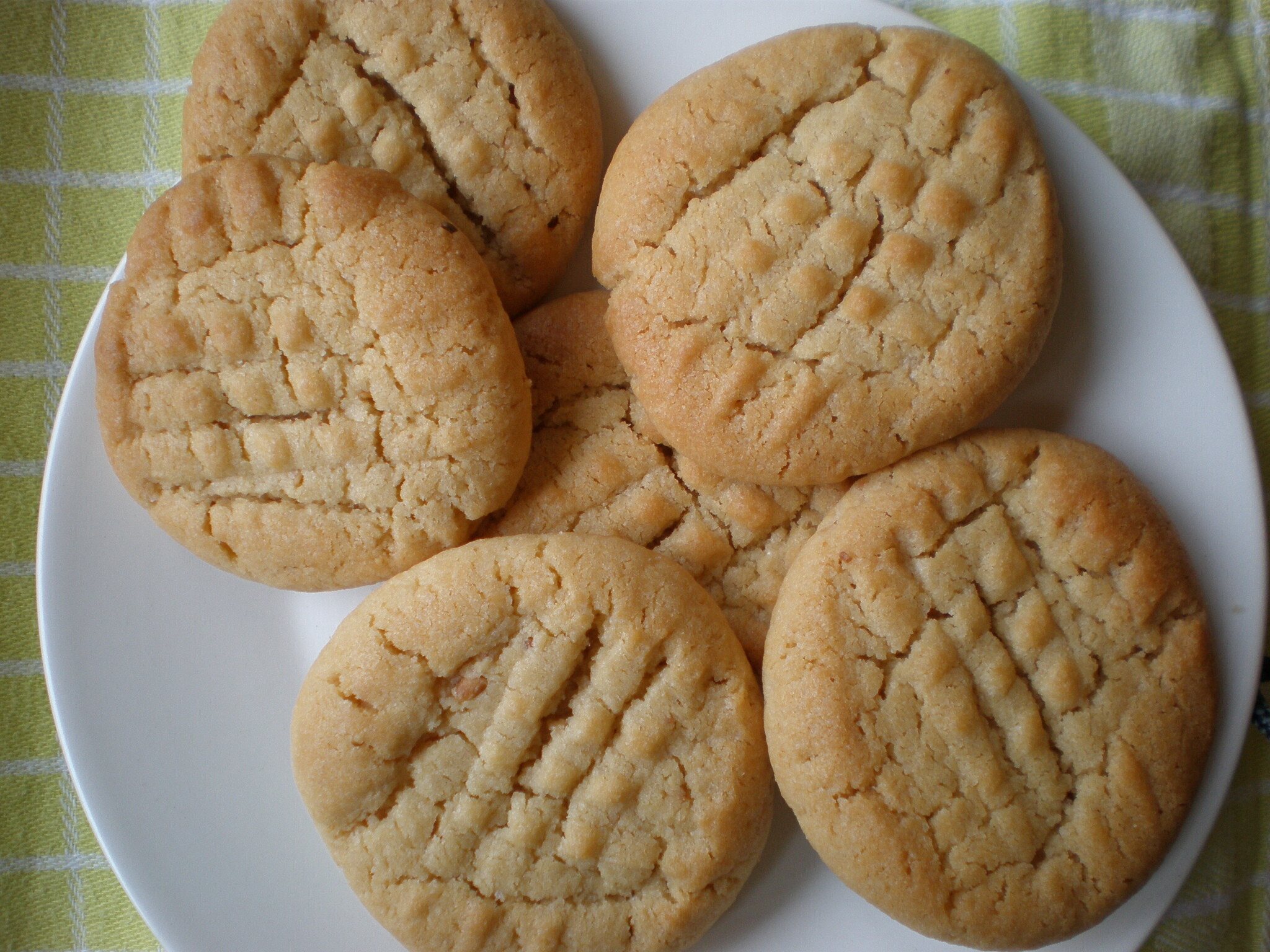 Peanut butter cookies with crisscross fork marks on a white plate