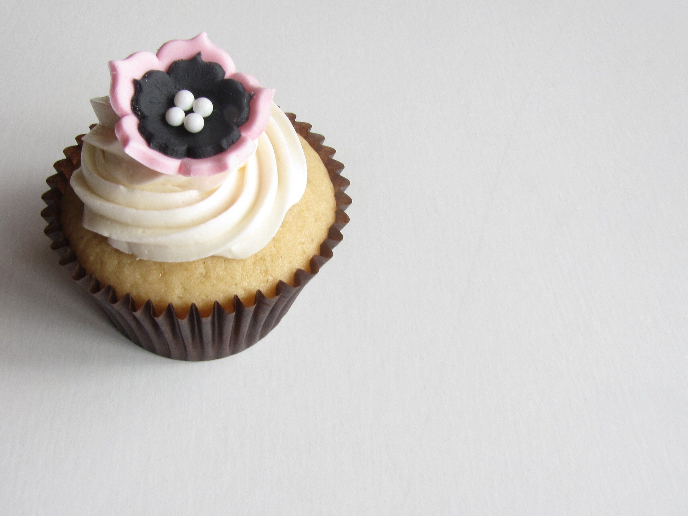 A vanilla cupcake with a swirl of buttercream and a decorative sugar flower